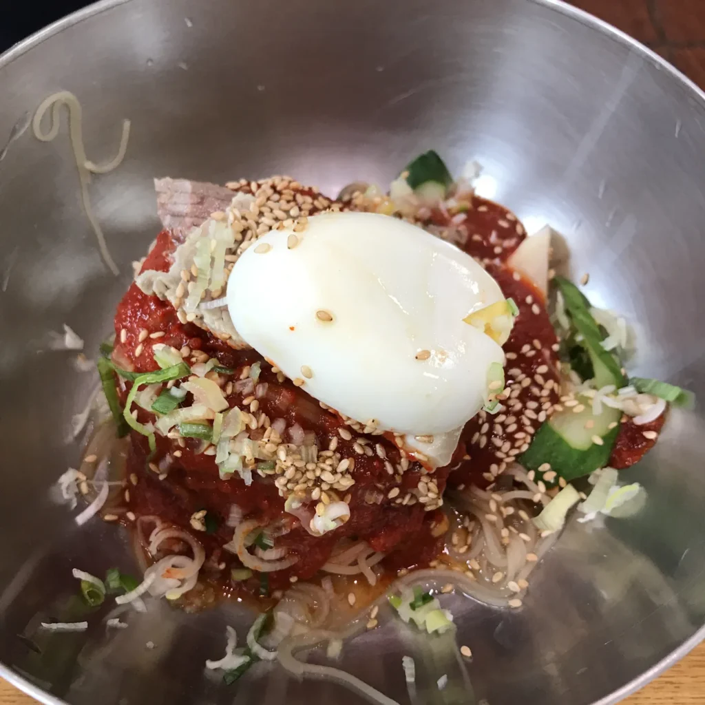 Bibim-naengmyeon com noodles frios cobertos por molho vermelho picante.