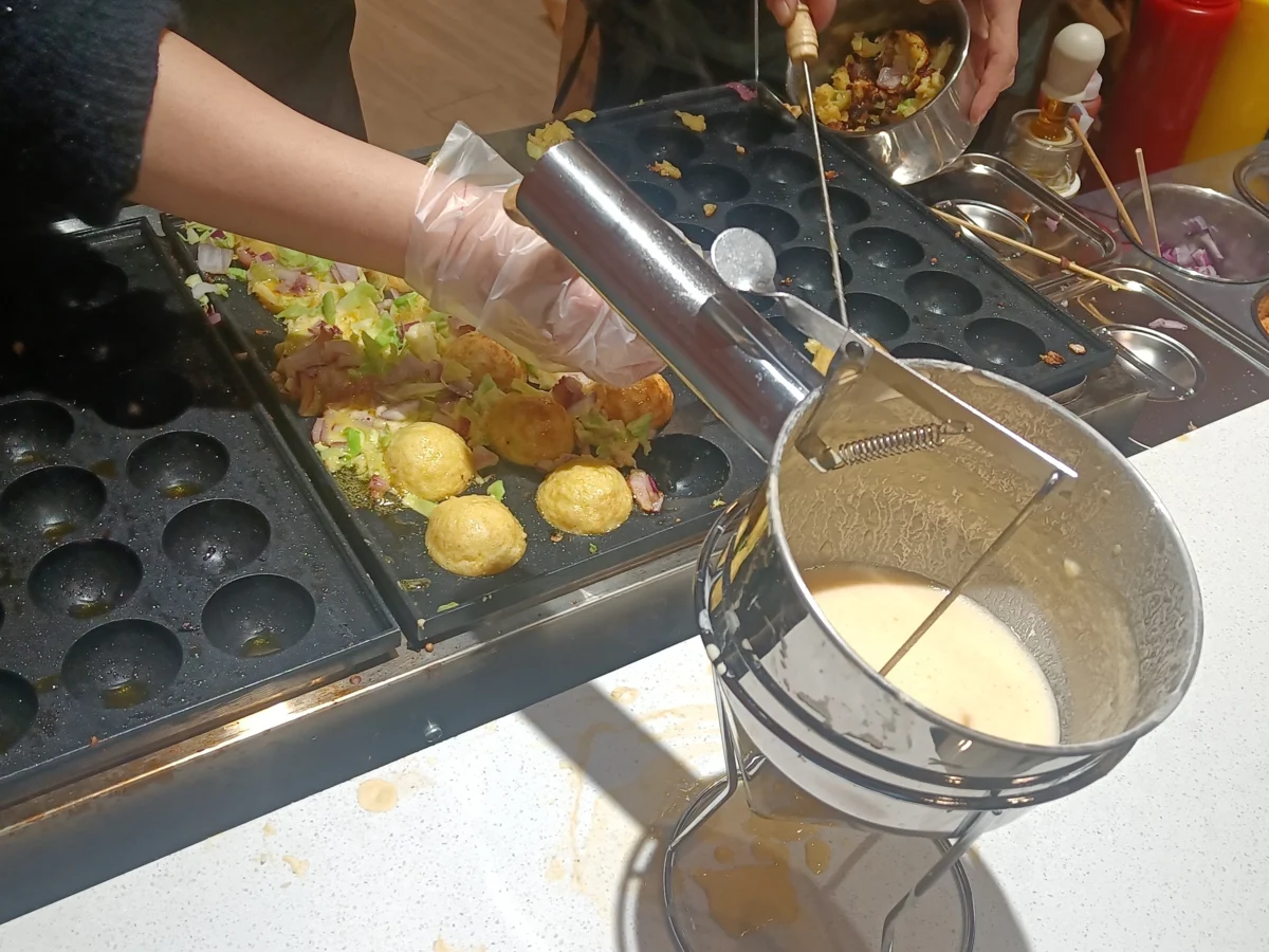 Takoyaki: O Que É e Como Fazer o Bolinho de Polvo Japonês | Comidas Asiáticas: Takoyaki sendo preparado em chapa com cavidades redondas