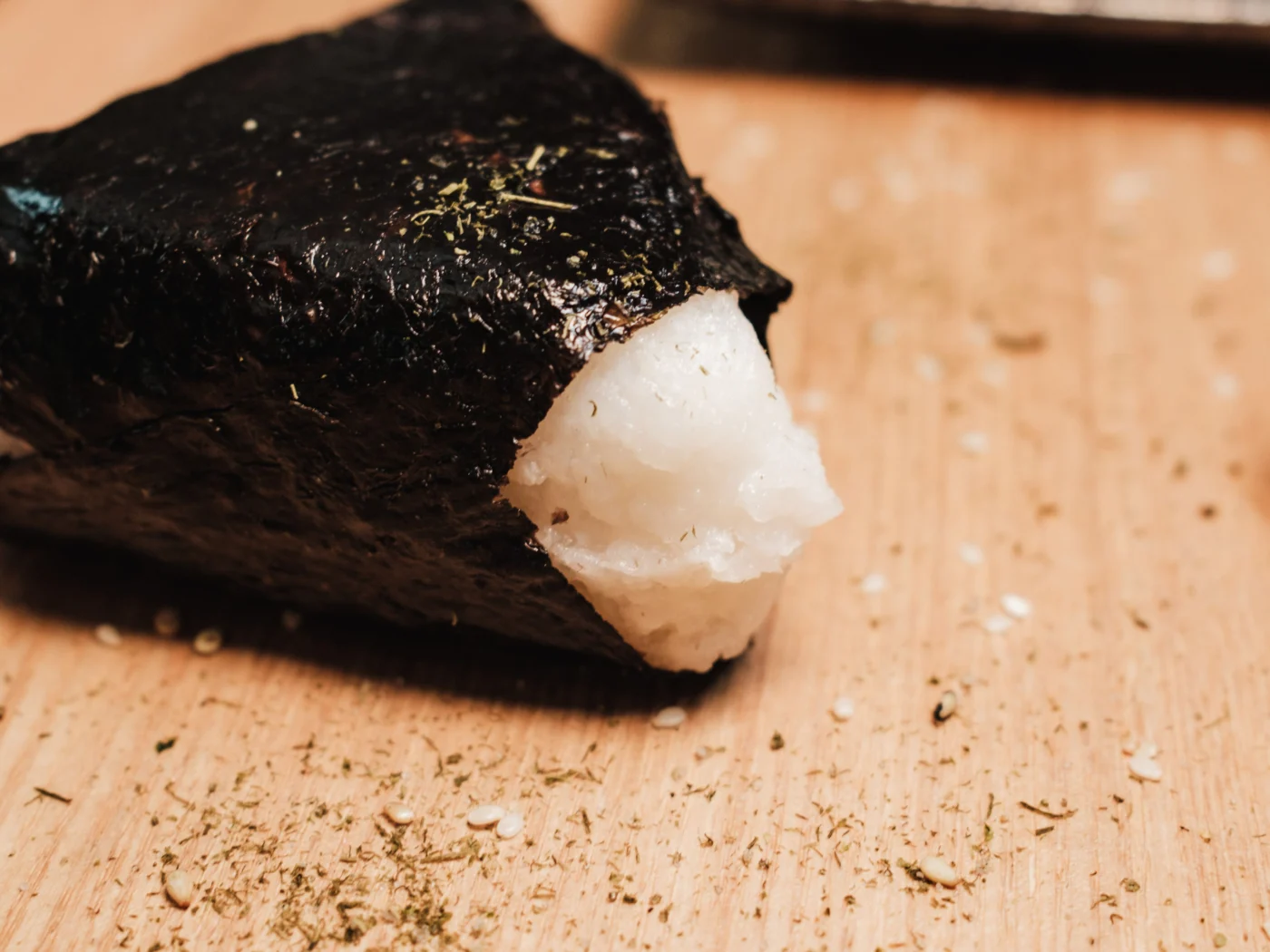 Onigiri japonês envolvido em nori sobre tábua de madeira