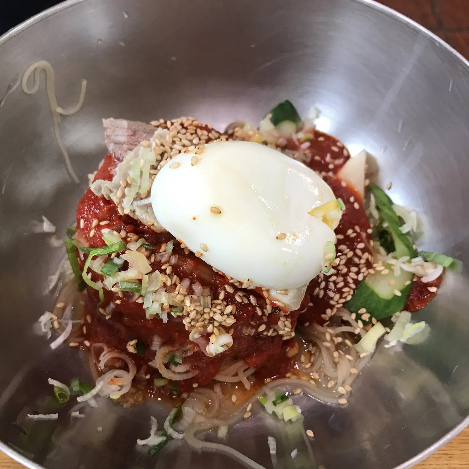 Bibim-naengmyeon com noodles frios cobertos por molho vermelho picante.
