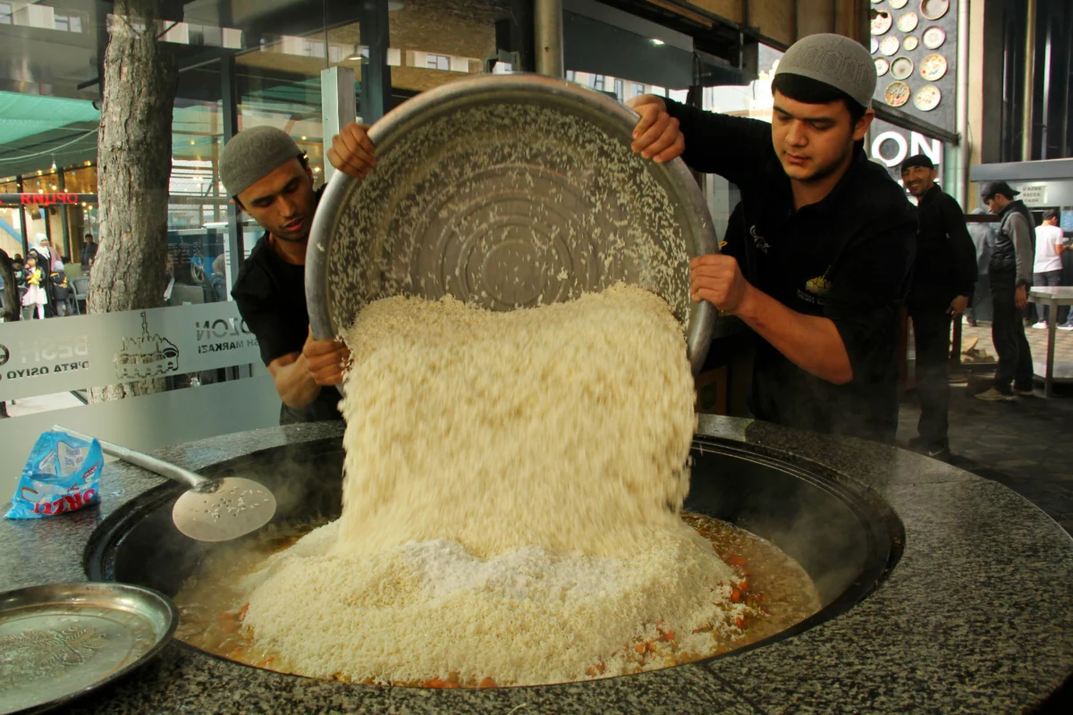 Arroz sendo colocado em um grande kazan durante o preparo de plov em Tashkent.