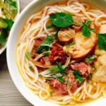 Tigela de bún bò Huế com macarrão, carne e ervas