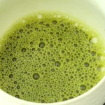 Tigela com matcha japonês verde preparado.