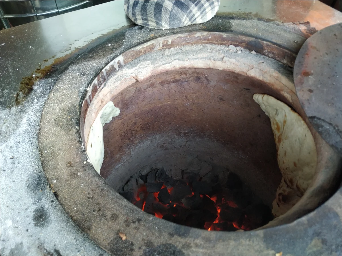 Naan: O que é e Como Fazer o Pão Indiano em Casa | Comidas Asiáticas: Pães naan colados na parede interna de um forno tandoor.