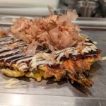 Okonomiyaki estilo Osaka com molho, maionese e coberturas japonesas