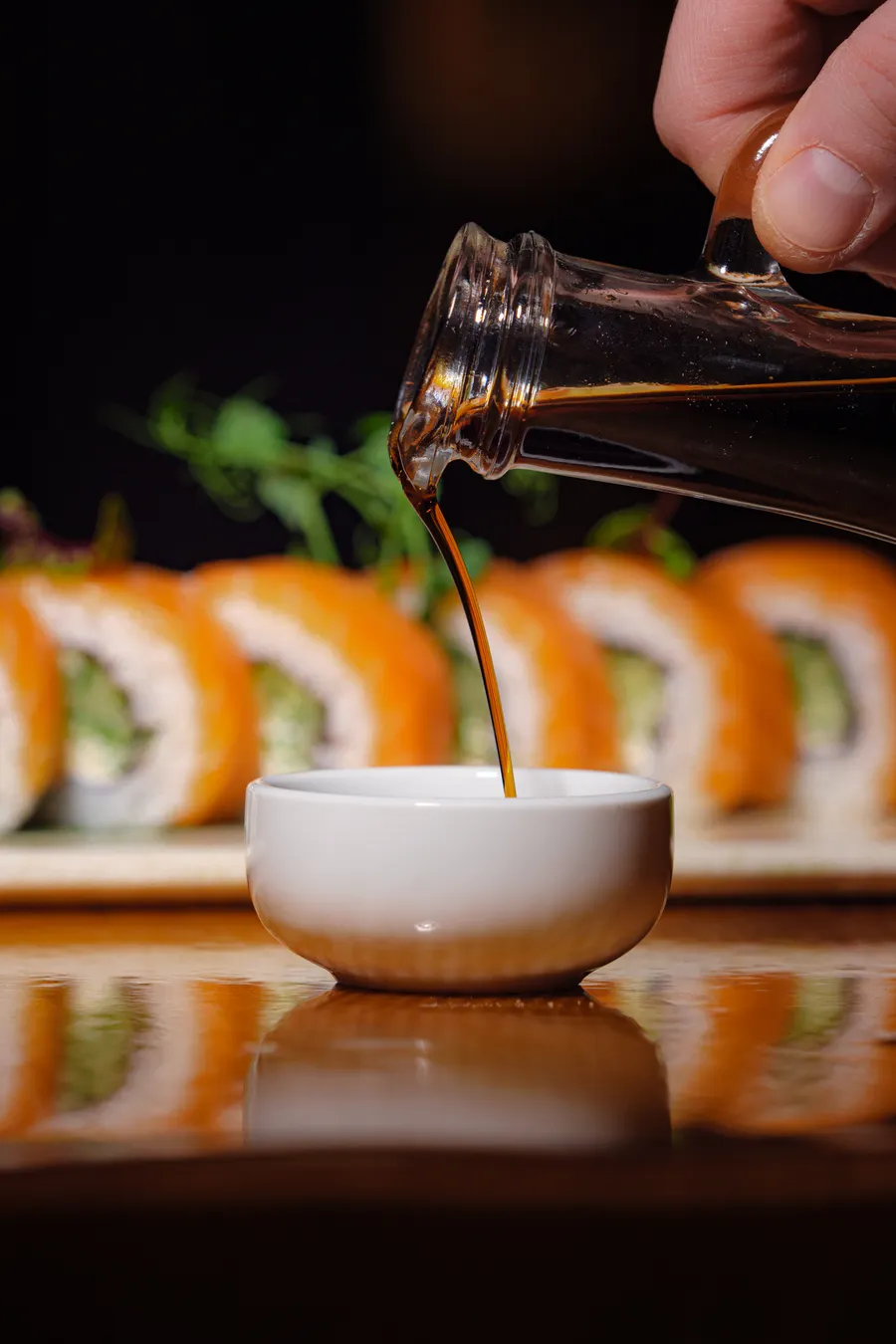Shoyu: O Que É, Tipos, Como Usar e Diferenças do Molho de Soja | Comidas Asiáticas Shoyu sendo servido em uma tigela com sushi ao fundo