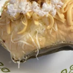Bibingka assada com queijo, ovo salgado e coco ralado sobre folha de bananeira
