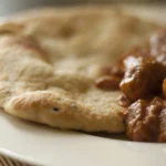 Butter chicken indiano com pedaços de frango ao molho vermelho cremoso de tomate e manteiga