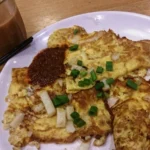 Carrot cake salgado de Singapura com pedaços de bolo de nabo branco dourados na frigideira e ovo