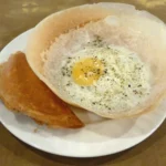 Egg hoppers do Sri Lanka, panquecas finas com bordas crocantes e ovo no centro