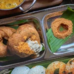 Idli: O Que É e Como Fazer o Bolinho Indiano no Vapor | Comidas Asiáticas: Bolinhos brancos de idli servidos em prato com sambar e chutneys no café da manhã indiano