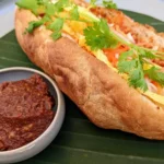 Khao jee pâté laosiano em baguete com patê, omelete, ervas e molho de pimenta