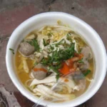 Kuy Teav: O Que É e Como Fazer a Sopa Cambojana | Comidas Asiáticas: Tigela de sopa cambojana de macarrão de arroz com caldo e acompanhamentos em Phnom Penh