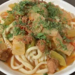 Lagman de macarrão com carne e legumes servido em prato fundo