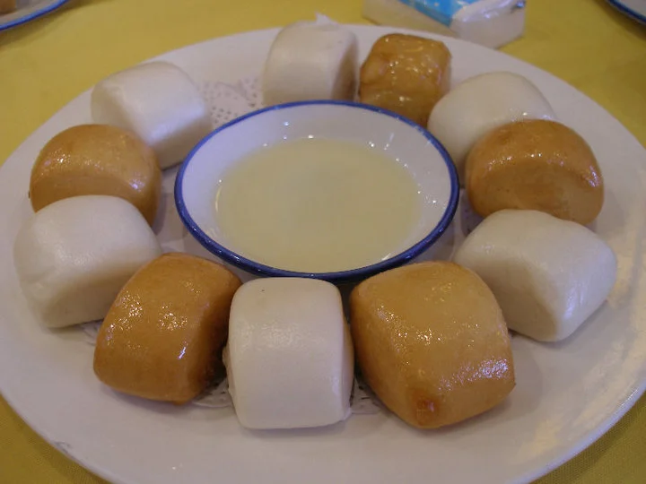 Pães mantou brancos e dourados em volta de um acompanhamento doce