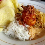 Prato de nasi uduk com arroz de coco, ovo com molho apimentado, bihun, tempeh e biscoito crocante