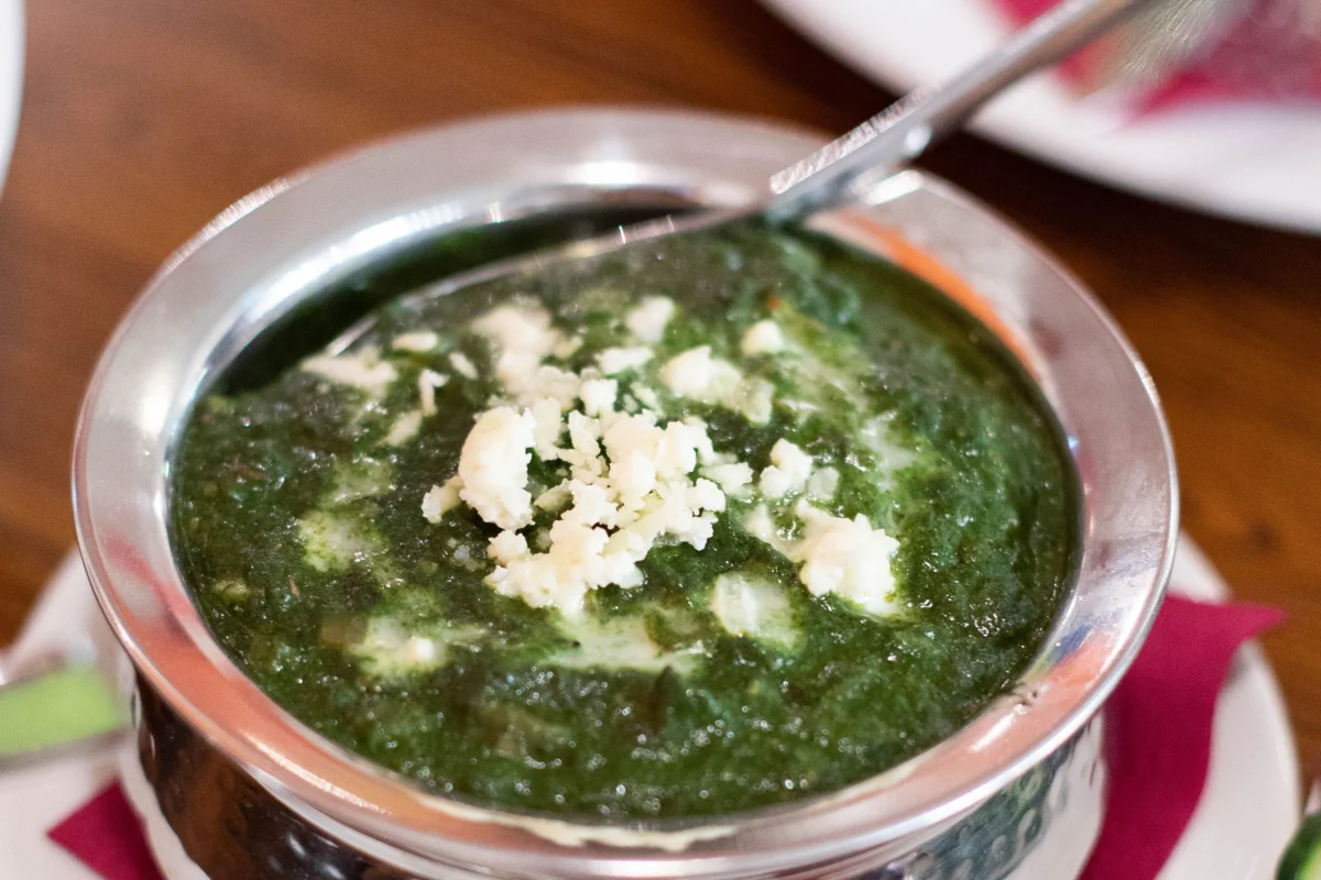 Palak paneer servido em tigela de metal com molho de espinafre