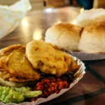 Vada pav de Mumbai com bolinho dourado de batata dentro de pão macio, acompanhado de chutney